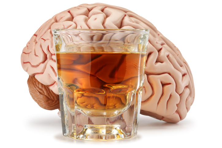 Shot glass of whiskey in front of a brain