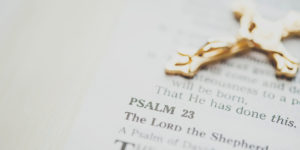 gold crucifix laying on bible open to Psalm 23 - catholic drug rehab