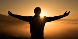 silhouette of man with arms open to sky during sunset - catholic rehab programs