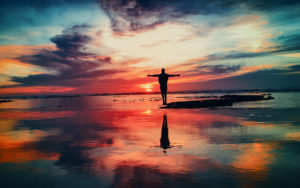 brilliant sunset with person silhouetted on a sand bar at sea - Christ centered addiction treatment