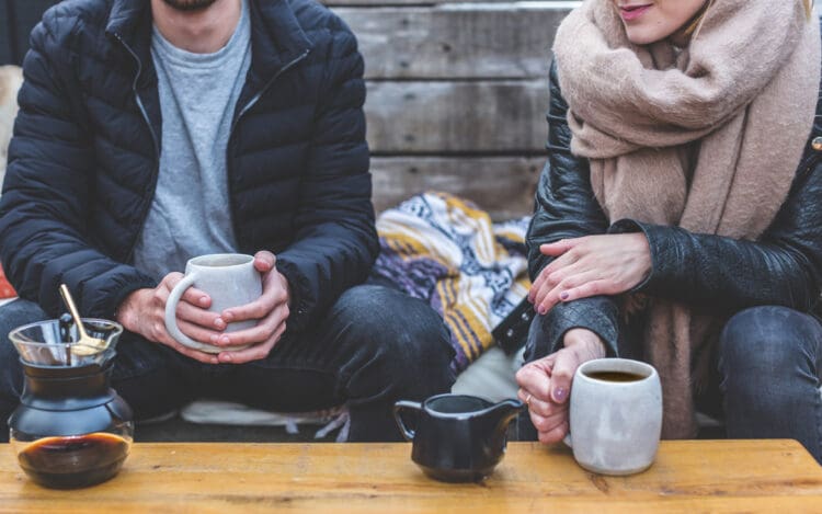 couple sitting and drinking tea outside in winter wearrebuilding trust after addiction