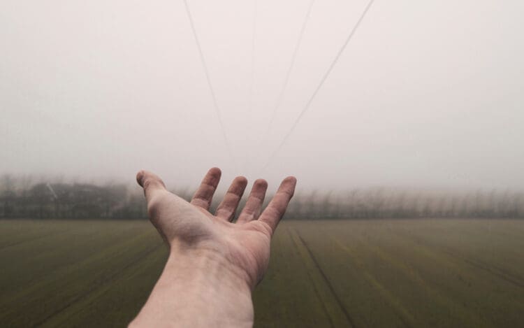 person holding hand out in front of them, palm up - trusting God in addiction treatment and recovery