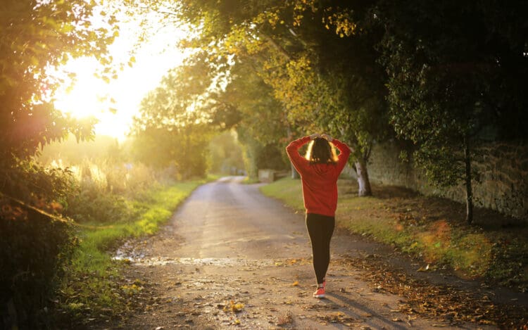 woman walking on trail with her hands on top of her head - drug withdrawal management