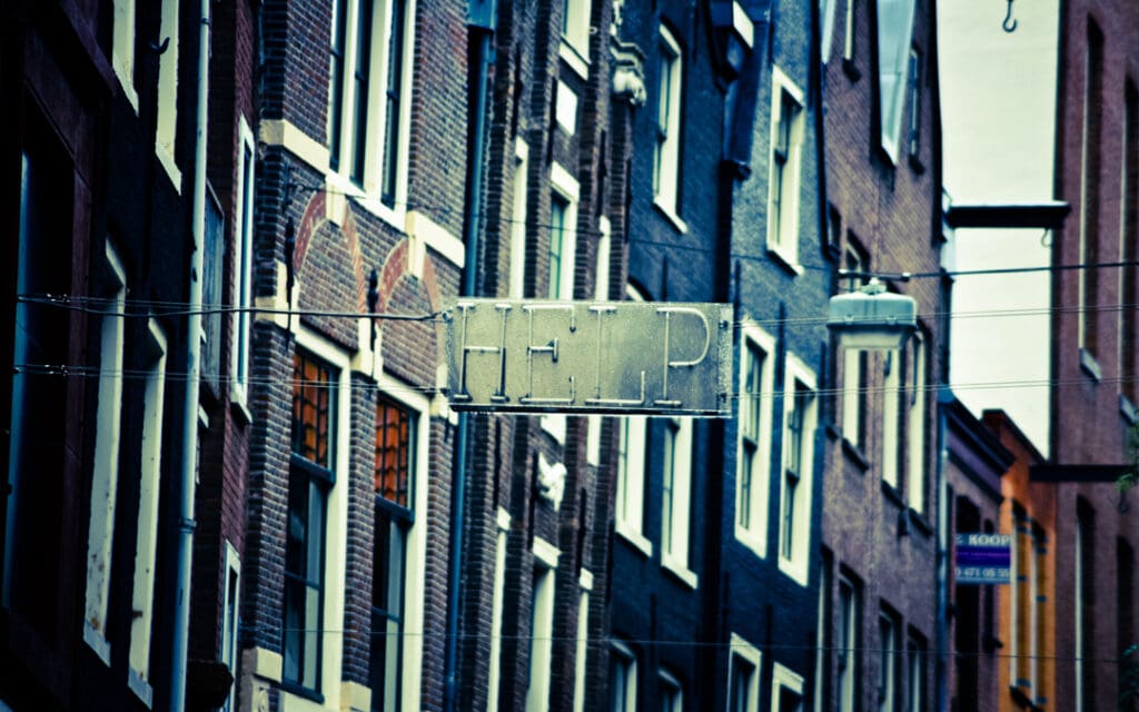 metal and neon 'HELP' sign hanging between brick buildingsreverse an overdose with naloxone