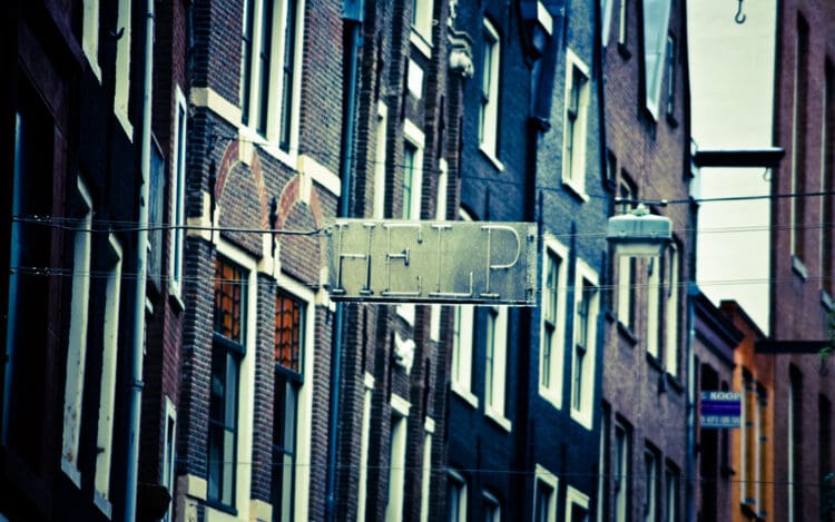 metal and neon 'HELP' sign hanging between brick buildingsreverse an overdose with naloxone