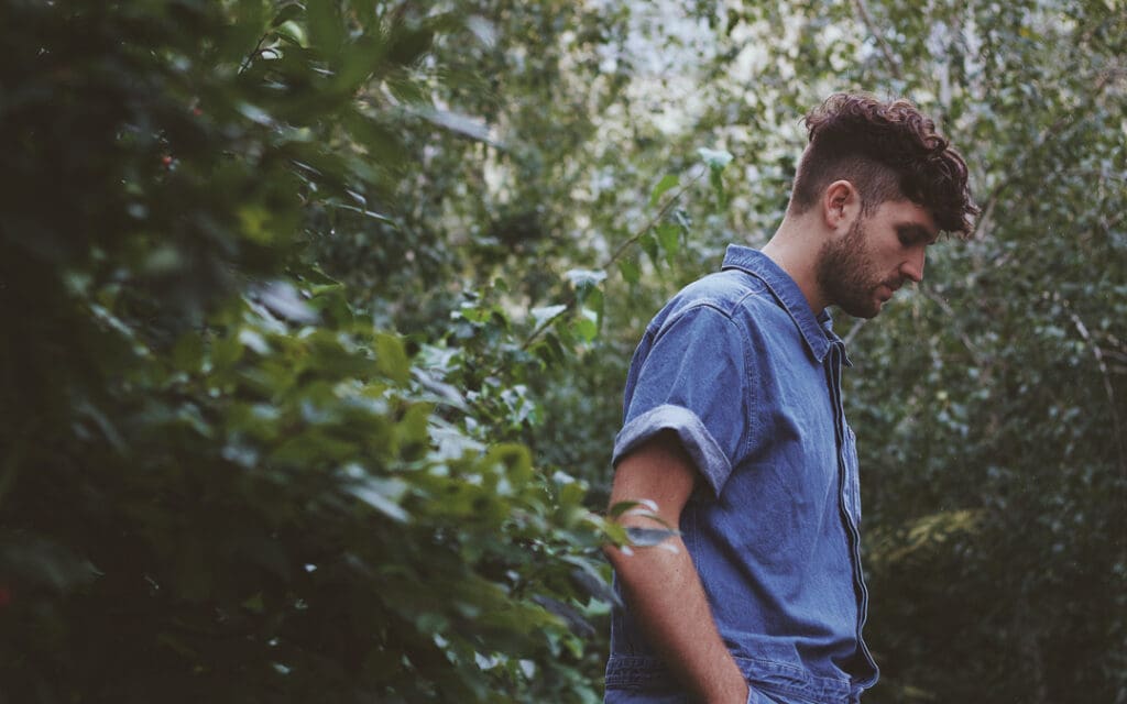 young solemn looking man walking in woods