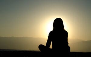 silhouette of person sitting on rooftop during sunset