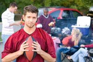 young man holding football at tailgate party