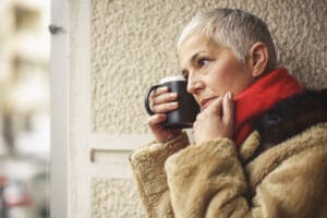 lovely senior woman drinking coffee or cocoa outside during the winter