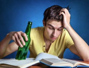 young man drinking beer while studying