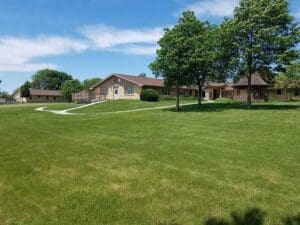 backyard of facility with green grass and trees