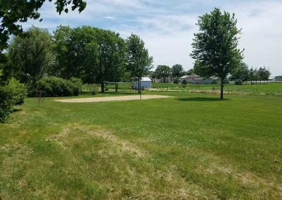 outdoors area with sand volleyball court surrounded by green trees
