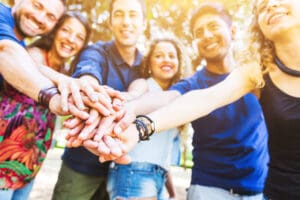 smiling group of friends with hands stacked in fellowship