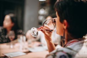 woman drinking red wine at dinner table - women