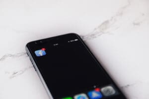 close up of phone on white marble table, with Facebook app icon showing - social media
