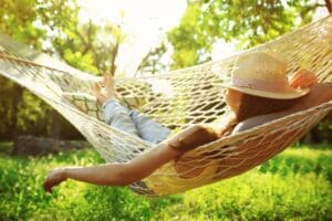 woman relaxing in backyard hammock - sober summer