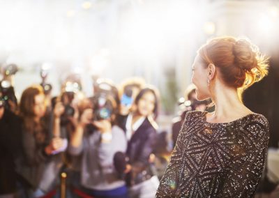 woman walking red carpet surrounded by flashing cameras and paparazzi - celebrities and addiction