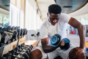handsome young Black man lifting free weights on a bench at the gym - fit