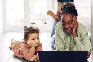 little girl and young woman looking at tablet computer together - parenting