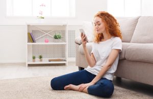 After Relapse, pretty red-haired young woman sitting on floor at home looking at the screen of her smart phone - relapse