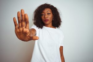 beautiful Black woman in a white tee-shirt holding her right hand out, palm up, making a stopping gesture - HALT