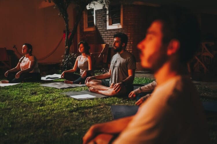 Photo by Matheus Bertelli: https://www.pexels.com/photo/people-practicing-yoga-outdoors-on-sunset-13870021/ meditation group