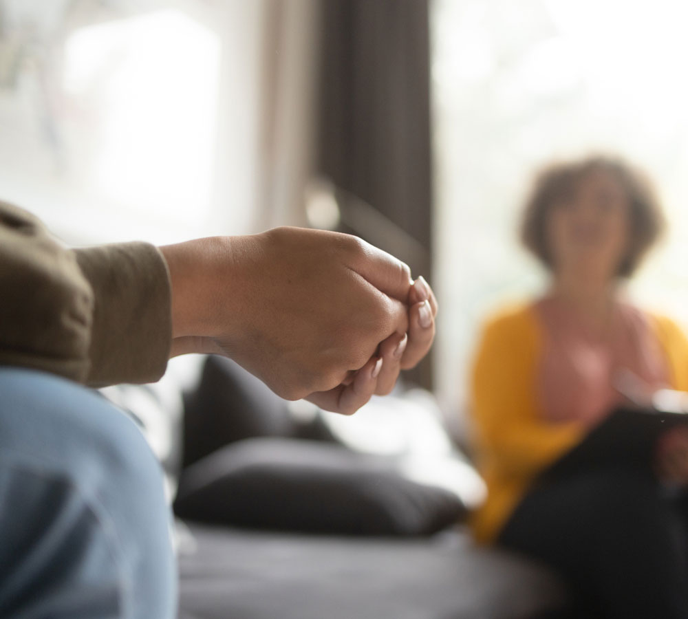 clinician talking to a client sitting on a couch in a residential treatment center