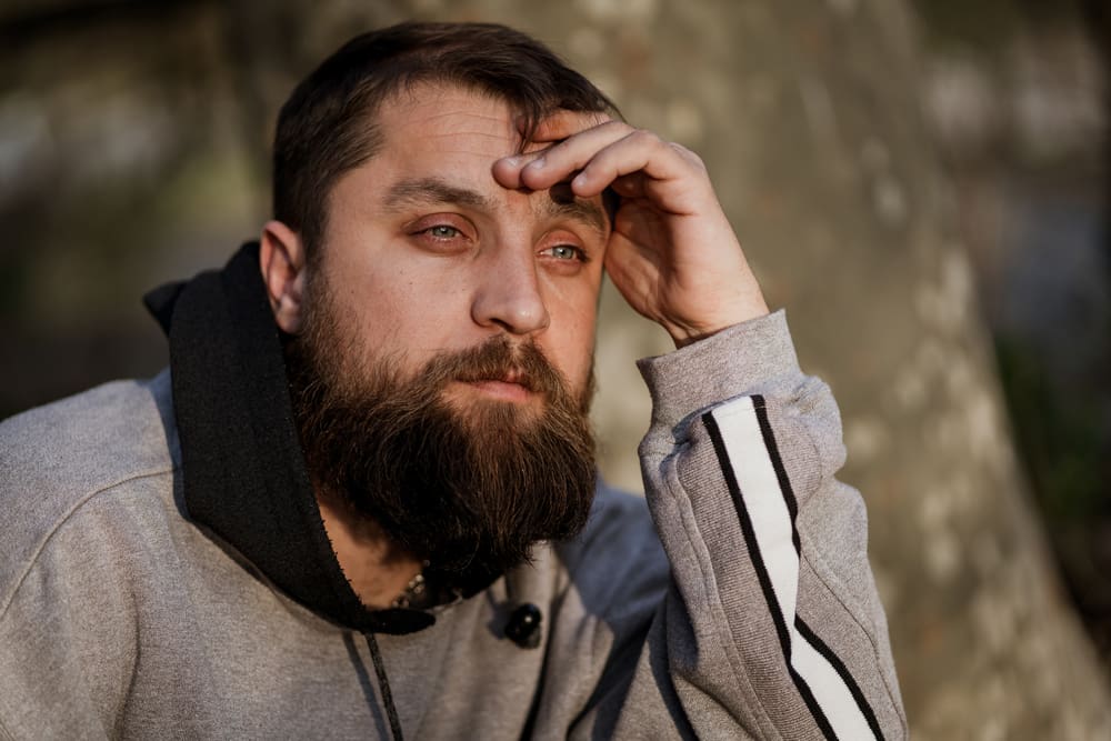 man who looks to be tired or sad, looking out pensively