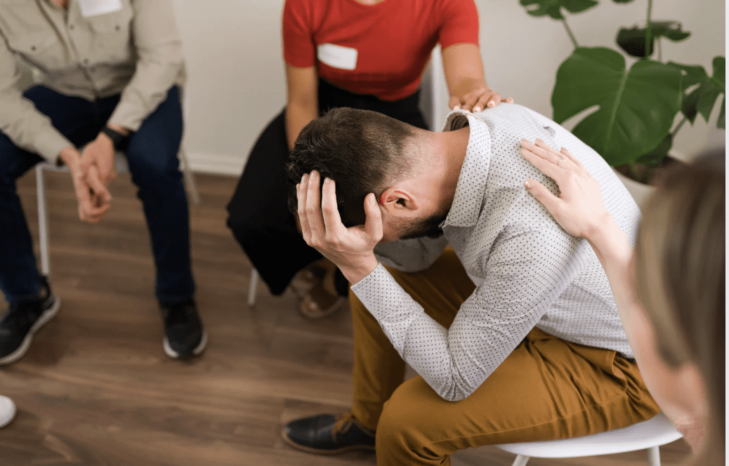 A distressed person being comforted by a group/